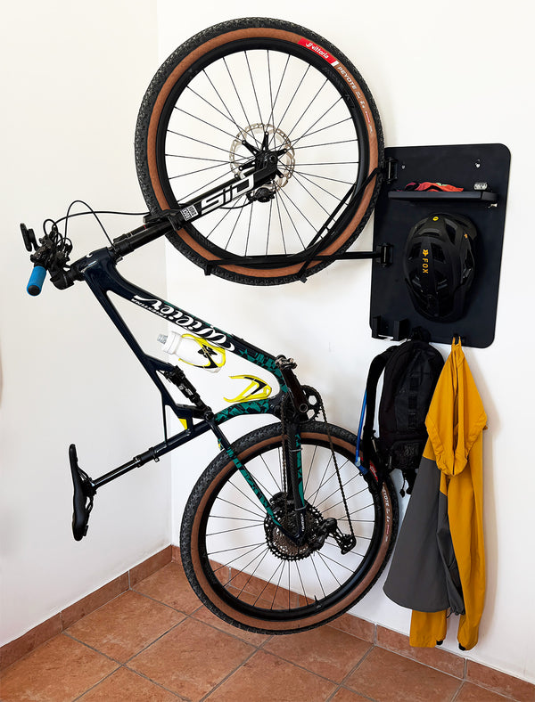 Bicycle mounted on a wall with a helmet and jacket hanging nearby.
